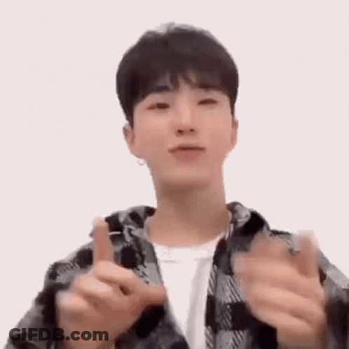 A Young Man In A Plaid Jacket Is Making A Heart Shape With His Hands . GIF