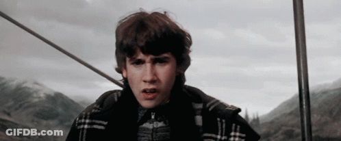 A Young Man In A Plaid Jacket Is Standing In Front Of Mountains GIF