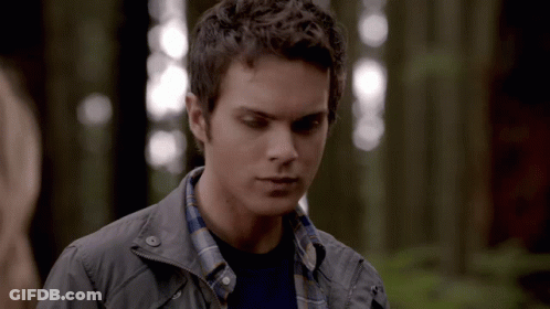 Young Man In Plaid Shirt And Grey Jacket In Woods GIF