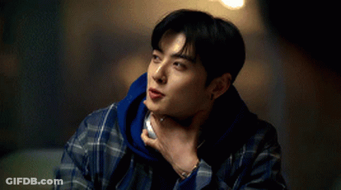 A Young Man In A Plaid Shirt Is Holding His Hand To His Chin . GIF