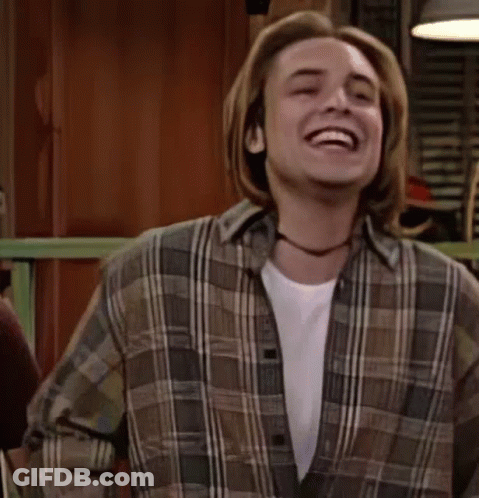 A Young Man In A Plaid Shirt Is Laughing And Dancing . GIF
