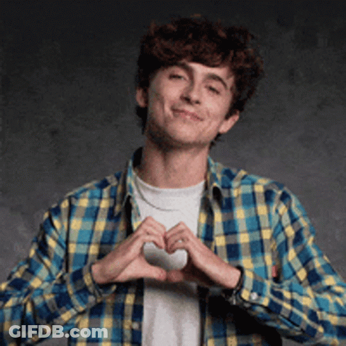 A Young Man In A Plaid Shirt Is Making A Heart With His Hands . GIF