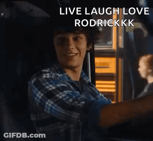 A Young Man In A Plaid Shirt Is Sitting In Front Of A Yellow School Bus With The Words Live Laugh Love Rodrickkkk GIF