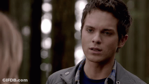 A Young Man In A Plaid Shirt Looks At A Woman In A Forest GIF