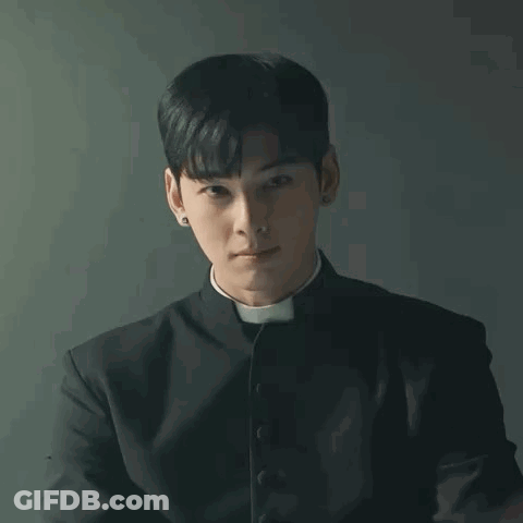 A Young Man In A Priest 'S Robe Is Praying With His Hands Together . GIF