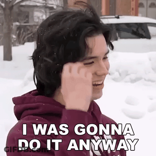 A Young Man In A Purple Hoodie Is Standing In The Snow And Talking On A Cell Phone . GIF