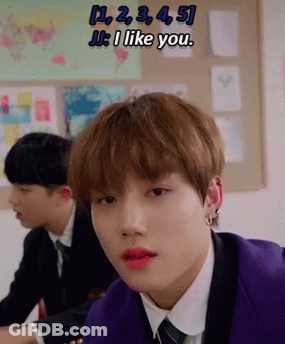 A Young Man In A Purple Suit And Tie Is Sitting At A Desk In A Classroom With Other Students . GIF