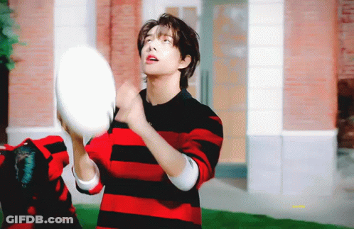 A Young Man In A Red And Black Striped Shirt Is Throwing A Frisbee In The Air . GIF