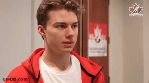 A Young Man In A Red Jacket Is Standing In Front Of A Poster That Says Canada GIF
