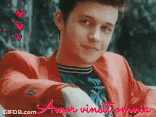 A Young Man In A Red Jacket With The Words Amor Vincit Omnia GIF