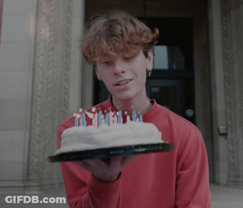 A Young Man In A Red Shirt Holds A Cake With Candles On It GIF
