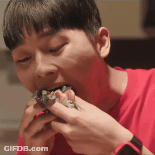 A Young Man In A Red Shirt Is Eating A Sandwich GIF