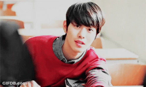 A Young Man In A Red Sweater Sits At A Desk GIF