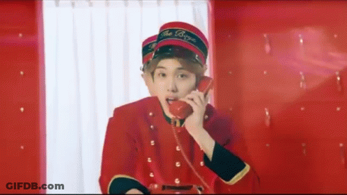 A Young Man In A Red Uniform Is Talking On A Red Phone . GIF