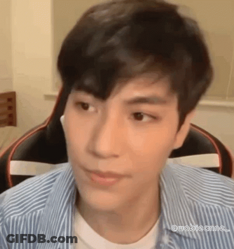 A Young Man In A Striped Shirt Is Sitting In A Chair And Looking At The Camera . GIF