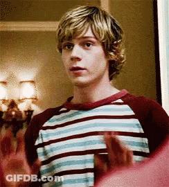 A Young Man In A Striped Shirt Is Standing In A Room With His Hands Outstretched . GIF