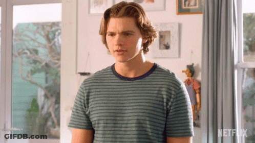 A Young Man In A Striped Shirt Is Standing In Front Of A Netflix Logo GIF