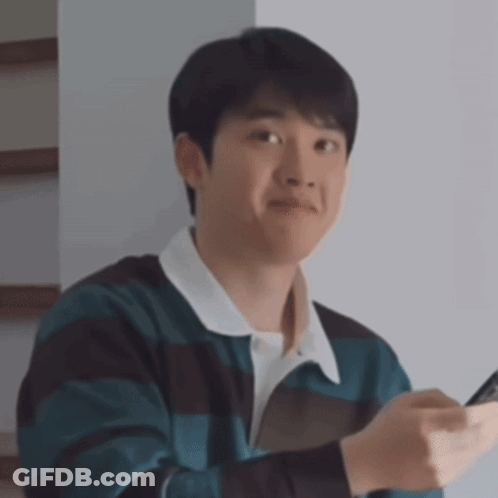 A Young Man In A Striped Sweater Is Holding A Cell Phone In His Hand . GIF