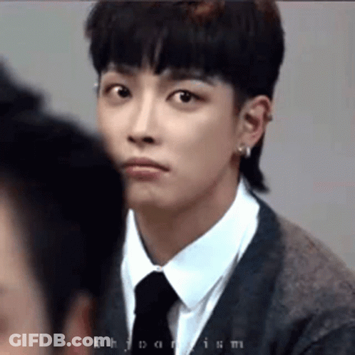 A Young Man In A Suit And Tie Is Looking At Another Man . GIF