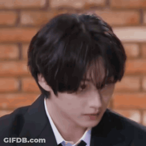 A Young Man In A Suit And Tie Is Looking Down . GIF