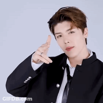 A Young Man In A Suit And Tie Is Making A Peace Sign With His Finger . GIF