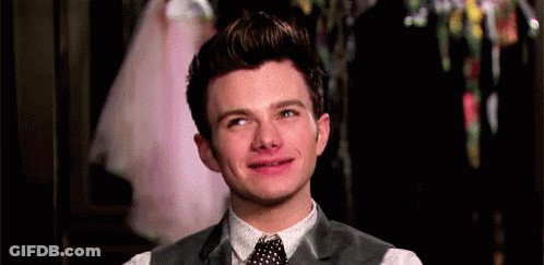 A Young Man In A Suit And Tie Is Smiling And Making A Funny Face . GIF