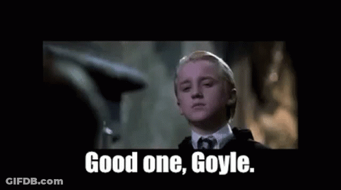 A Young Man In A Suit And Tie Is Standing In A Dark Room . GIF