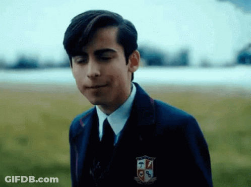 A Young Man In A Suit And Tie Is Standing In A Field With His Mouth Open . GIF