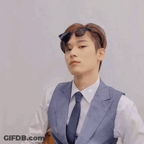 A Young Man In A Suit And Tie Is Wearing Sunglasses And Giving A Thumbs Up . GIF