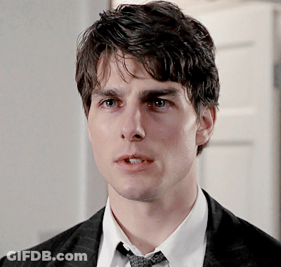 A Young Man In A Suit And Tie Looks At The Camera GIF