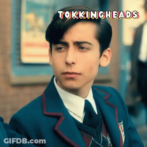 A Young Man In A Suit And Tie With The Words Tokingheads Written Above Him GIF