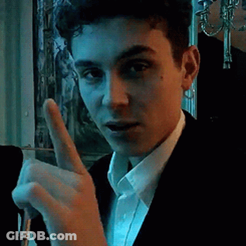 A Young Man In A Suit And White Shirt Is Giving A Thumbs Up Sign GIF