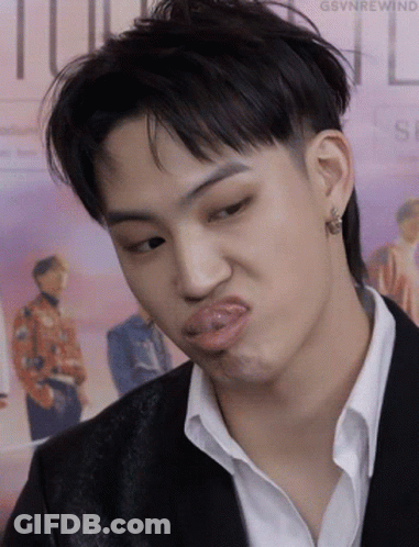 A Young Man In A Suit And White Shirt Is Making A Funny Face . GIF