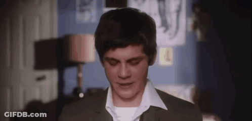 A Young Man In A Suit And White Shirt Is Standing In A Room And Looking Down . GIF