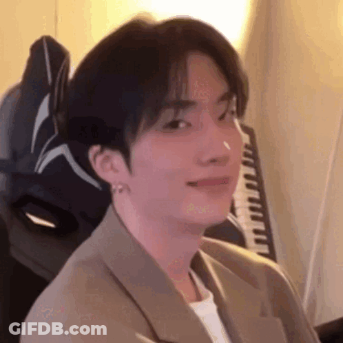 A Young Man In A Suit Is Sitting In A Chair In Front Of A Keyboard . GIF