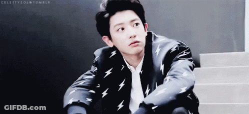 A Young Man In A Suit With Lightning Bolts On It Is Sitting On Stairs . GIF