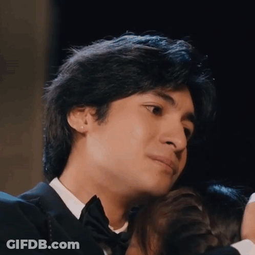 A Young Man In A Tuxedo Is Hugging A Woman GIF