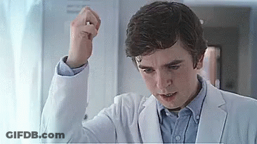 A Young Man In A White Coat Is Holding His Fist Up In The Air . GIF
