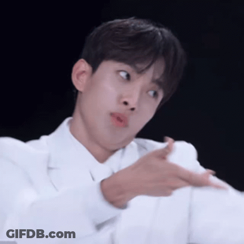 A Young Man In A White Coat Is Making A Funny Face While Pointing At Something . GIF