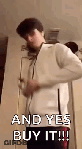 A Young Man In A White Jacket Is Standing In Front Of A Door . GIF