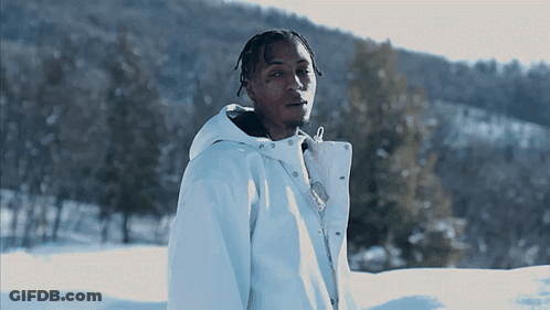A Young Man In A White Jacket Stands In The Snow GIF