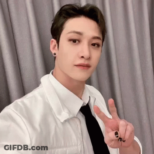 A Young Man In A White Shirt And Tie Is Giving The Peace Sign . GIF