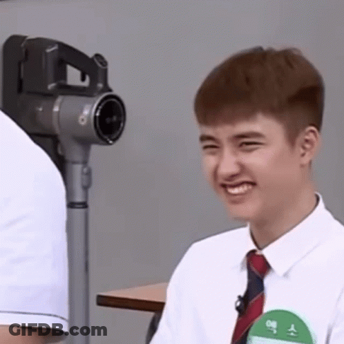 A Young Man In A White Shirt And Tie Is Smiling While Sitting At A Table . GIF