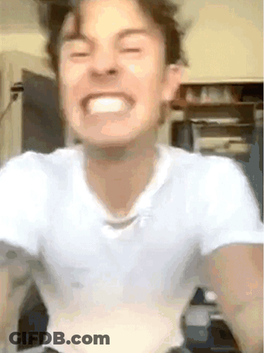 A Young Man In A White Shirt Is Making A Funny Face . GIF