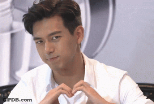 A Young Man In A White Shirt Making A Heart Shape With His Hands GIF