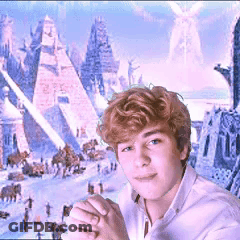 A Young Man In A White Shirt Stands In Front Of A Painting Of Pyramids GIF