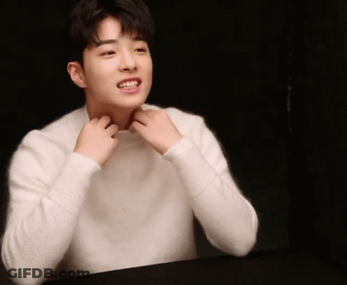 A Young Man In A White Sweater Is Smiling GIF