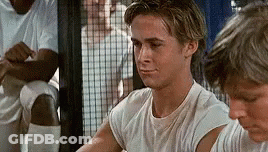 A Young Man In A White T-Shirt Is Sitting Next To Another Young Man In A Locker Room . GIF