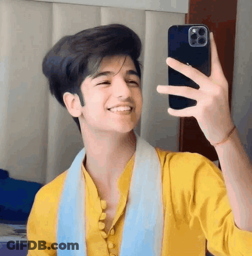 A Young Man In A Yellow Shirt Is Taking A Selfie With His Cell Phone . GIF