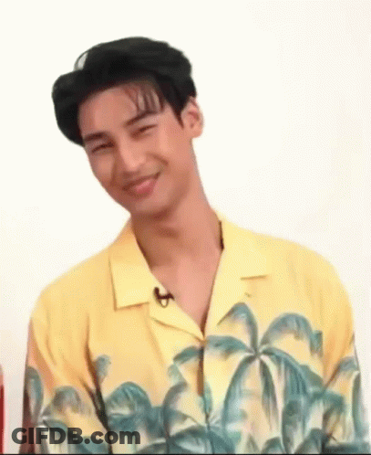 A Young Man In A Yellow Shirt With Palm Trees On It Is Smiling . GIF